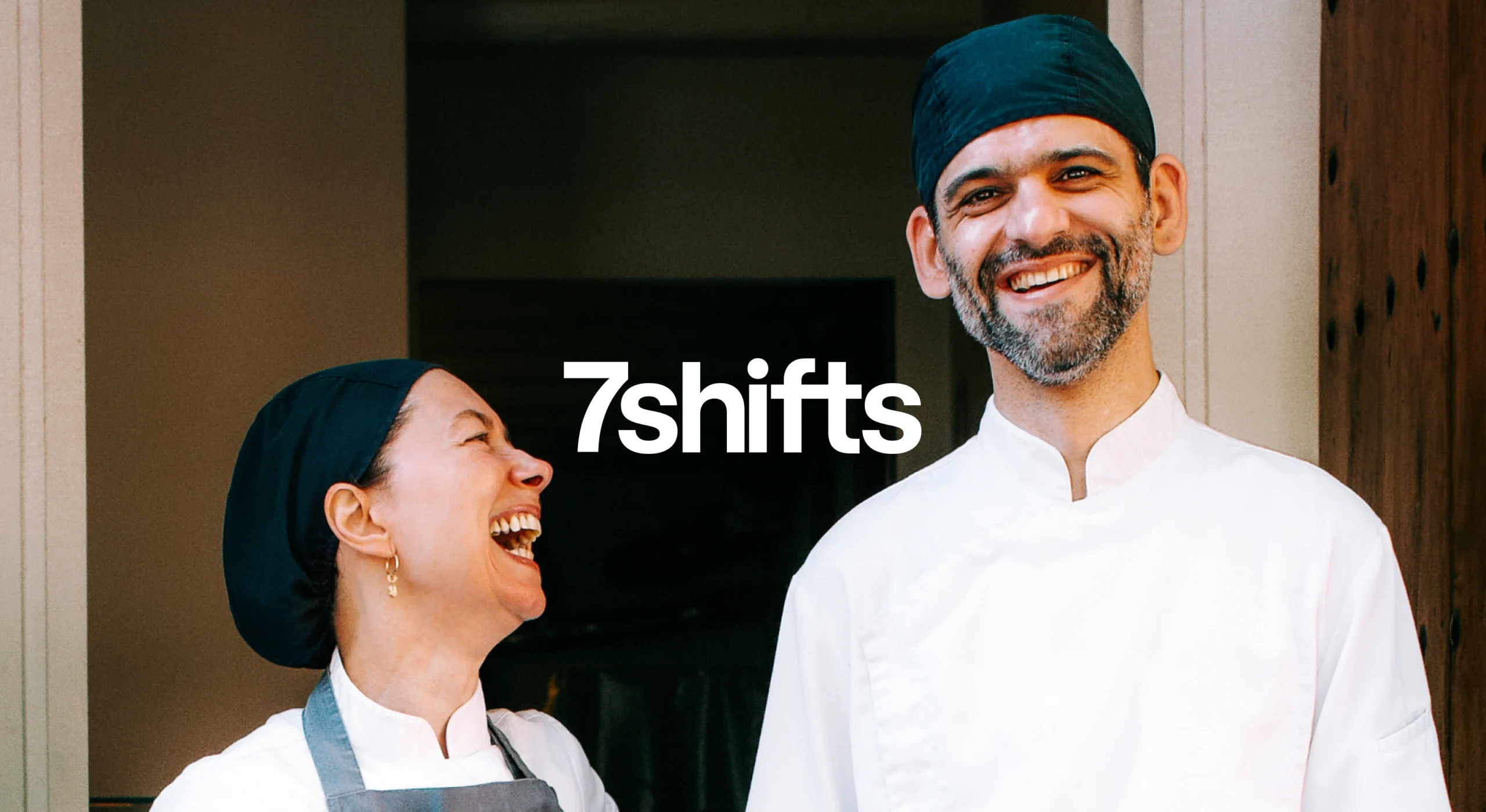 Male and female chef smiling and laughing.